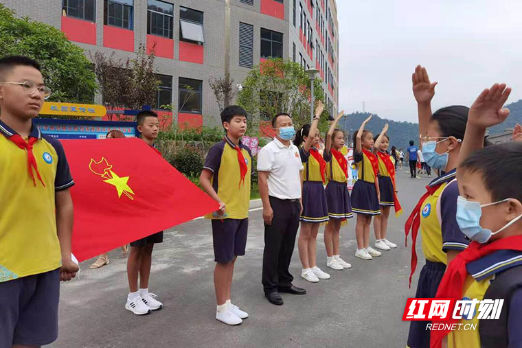 吉首市乾雅小学,少先队员举着队旗迎接队员们归校,每一位进校的少先