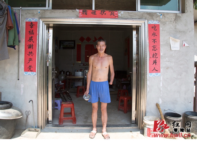 黄春波，凼底乡桴江村胡家组贫困户，眼、手残疾，2016年通过易地搬迁安置，从河对面的土砖屋搬至新居，搬新家时特意请人写了一幅对联：吃水不忘挖井人，幸福感谢共产党，以表达对党和政府的感激之情。同时黄春波在扶贫工作组的帮助下，以奖代扶养殖了跑山鸡和麻鸭，每年收入在2万元左右。（陈斌 摄）
