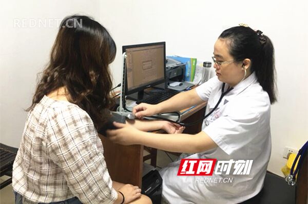 怀孕后仍坚持上班的医师冯宁波正为病人量血压。