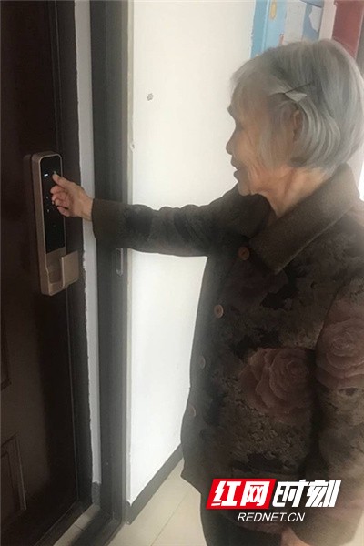 张月琴老人正在使用指纹锁开门.