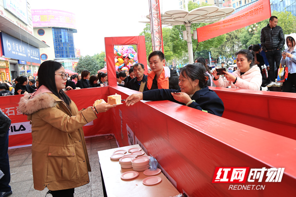 娄底天虹总经理陈爱萍为顾客分发蛋糕。