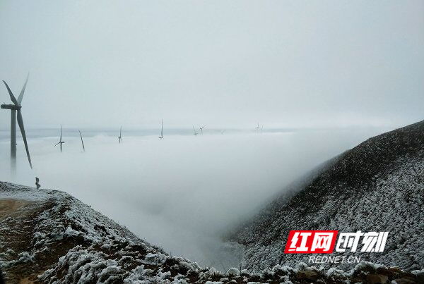 十余台大型风力发电机在冰雪云海中若隐若现，恍如海市蜃楼。