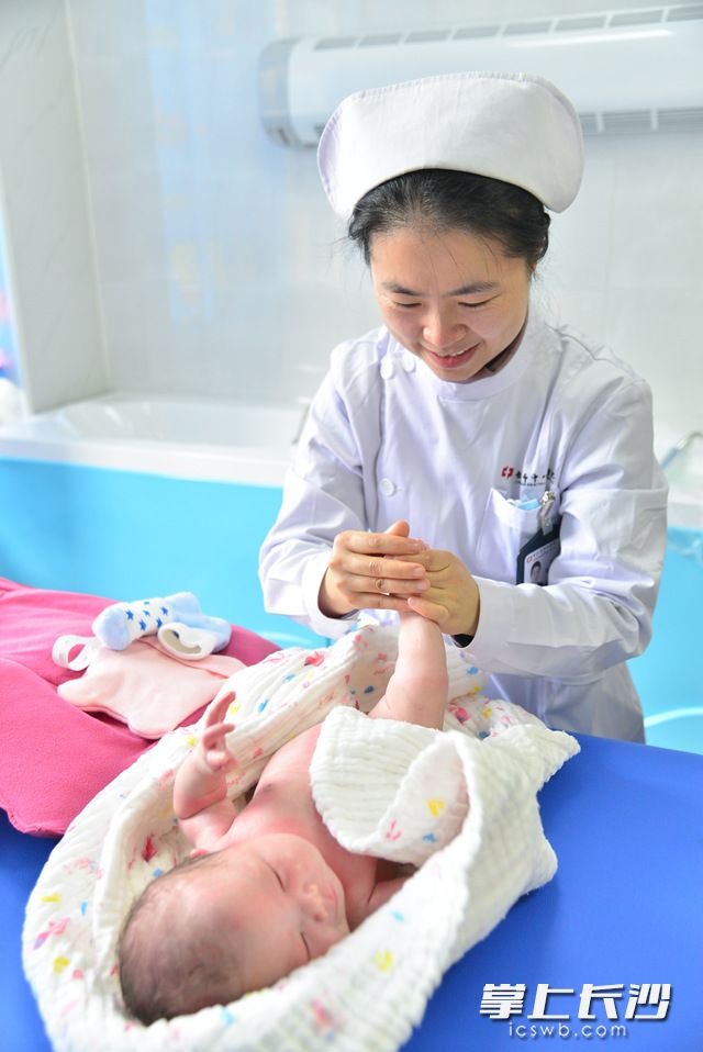 在长沙市中心医院新生儿健康门诊，胡娟教奶爸奶妈给新生儿做抚触。长沙晚报通讯员 陈颖 摄