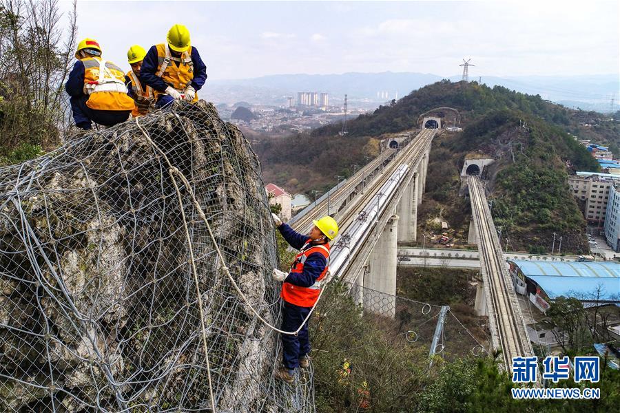 2月21日，贵阳高铁工务段工作人员在沪昆高铁一处隧道上方处理危石（无人机拍摄）。中国铁路成都局集团有限公司贵阳高铁工务段主要负责贵州省境内部分沪昆高铁、贵广高铁等路桥设备及沿线安全检查任务，辖区内高铁穿梭于喀斯特地貌间，沿线石山遍布。为了防止山石崩落危及铁路行车安全，上山搜山扫危成了贵阳高铁工务段工作人员的重要工作。他们爬山崖、攀绝壁，对悬崖上每一块可能松动掉落的岩石进行仔细观测和检查，在有落石隐患的地方加装防护网。工作劳动强度大，危险系数高，但他们依然无怨无悔地守护在悬崖上，保障旅客的出行安全。新华社记者 刘续 摄