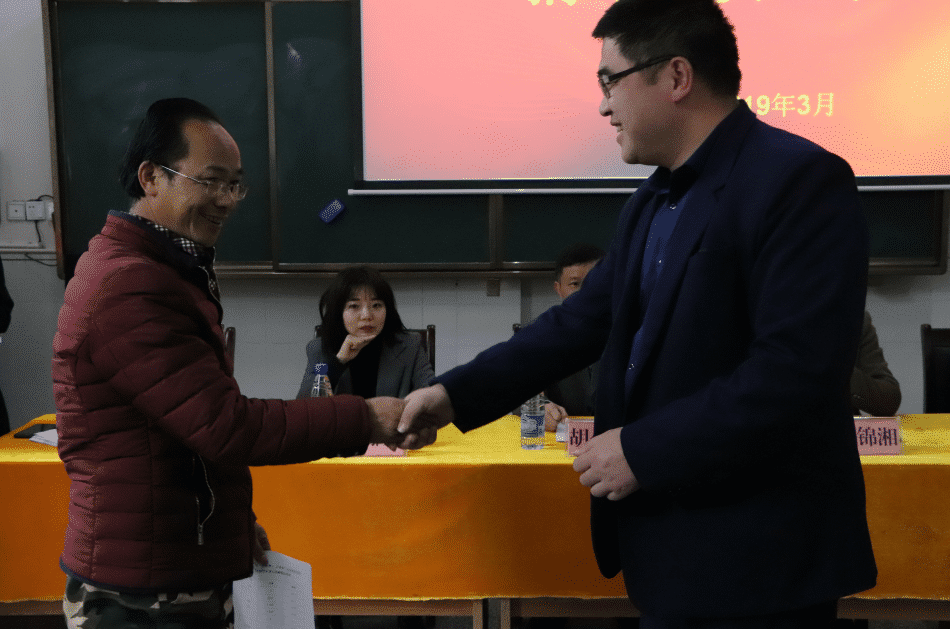 图为吉首大学商学院代表向塔卧苏区小学代表递交捐赠物品清单.png