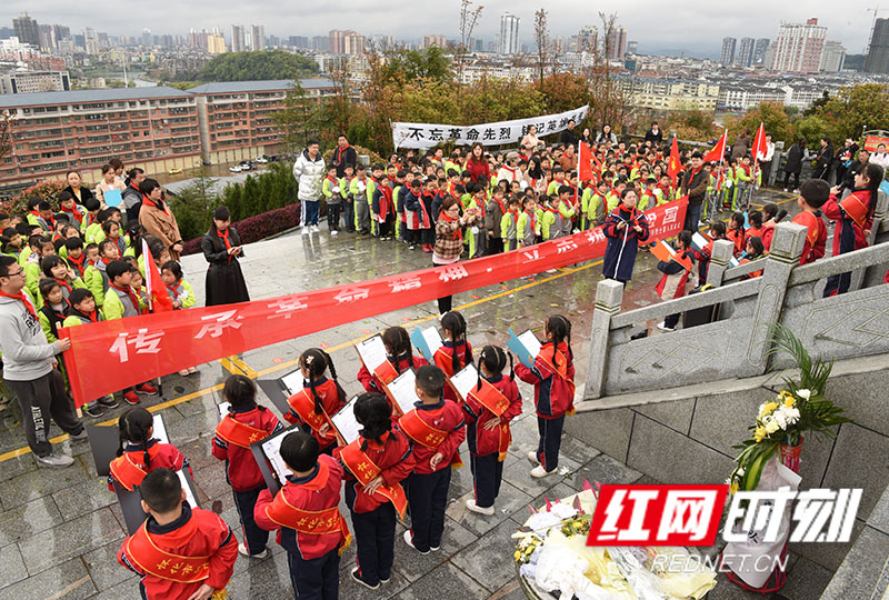 怀化市舞水小学西校区全体师生站在烈士塔下阅读《中国少年说》。