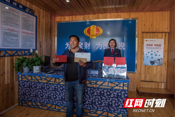 图为 湘西十八洞村村民杨再康从刚刚揭牌成立的“十八洞便民办税服务点”工作人员手中接过办好的增值税和通用定额发票，脸上笑开了花_meitu_3.jpg