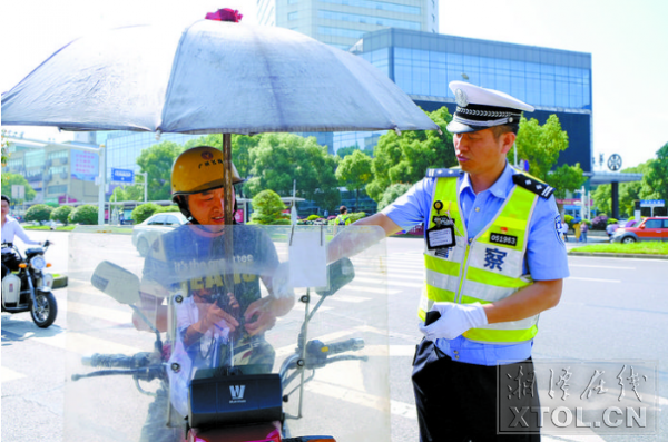 潘朝阳在建设路口执勤，对非法安装遮阳伞的摩托车车主进行教育。 （记者 方阳 摄）