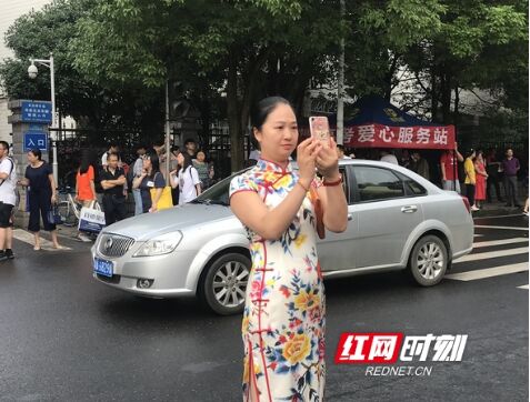 在拍考场门口的家长，她的朋友圈配文应该是“孩子，加油吧”！