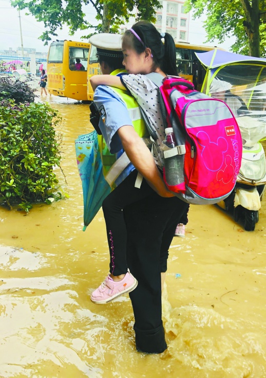 6月10日，新田县龙泉第五完全小学，民警护送三年级(10)班学生到安全地带。当天，该县遭遇强降雨，位于舂陵河畔的龙泉第五完全小学被倒灌的河水浸漫，学校立即启动紧急预案。（刘忠平 摄）