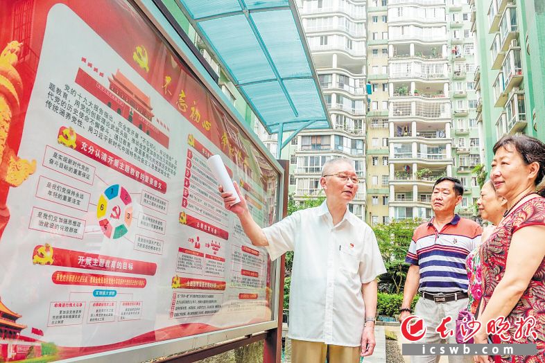 李铁军(左一)带领社区党员和群众在党建宣传栏前进行政治学习。长沙晚报全媒体记者 陈飞 摄