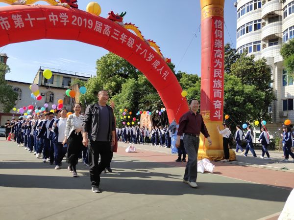成人礼活动中,校长(前排右)、书记(前排左)带领学生走过“成人门”。