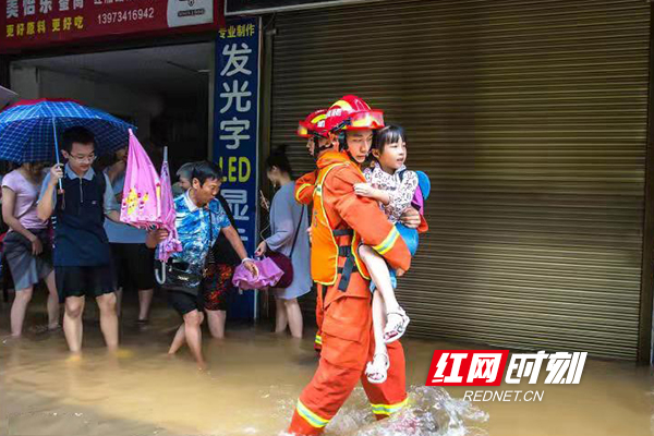 “孩子,别动!水很深,我抱你过去!”在红湘北路,由于河水倒灌,街面积水很深。为了群众安全,消防战士采取或背、或抱、或牵或扶等方式,把群众转移出去。