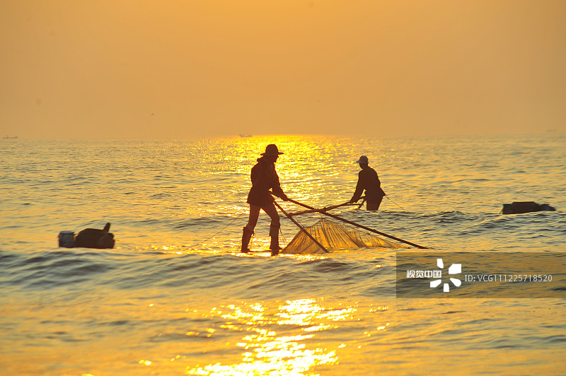 山东省日照海滨国家森林公园内的海边，渔民们迎着朝阳，踩着高跷在海里捕捞小虾。踩着“高跷”捕小虾，曾经是当地渔民们的重要生活来源，随着渔业资源的枯竭，以及从事这一古老的劳作方式的人也越来越少了，在不久的将来，也许会消失在人们的视线中。