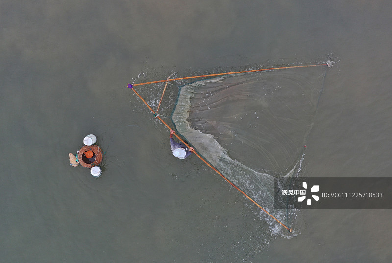 山东省日照海滨国家森林公园内的海边，一位渔民在海里捕捞小虾。