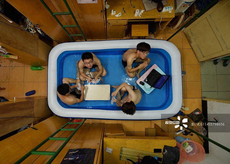 2014年08月05日，湖北省武汉市，江城持续高温，大学里留校的学子们想方设法避暑纳凉。华中师范大学一学生寝室过道上，放了个小“游泳池”，几位大学生坐在水中或打牌，或上网，非常惬意。小徐同学告诉记者，这个小水池花了几百块钱，里面可以同时躺两个人睡觉，这种避暑神器实用凉爽，但享受一次颇费功夫。从打气到注够水得花一个小时。不过幸亏自己的寝室离公共洗漱间近，注水方便，占了地利。