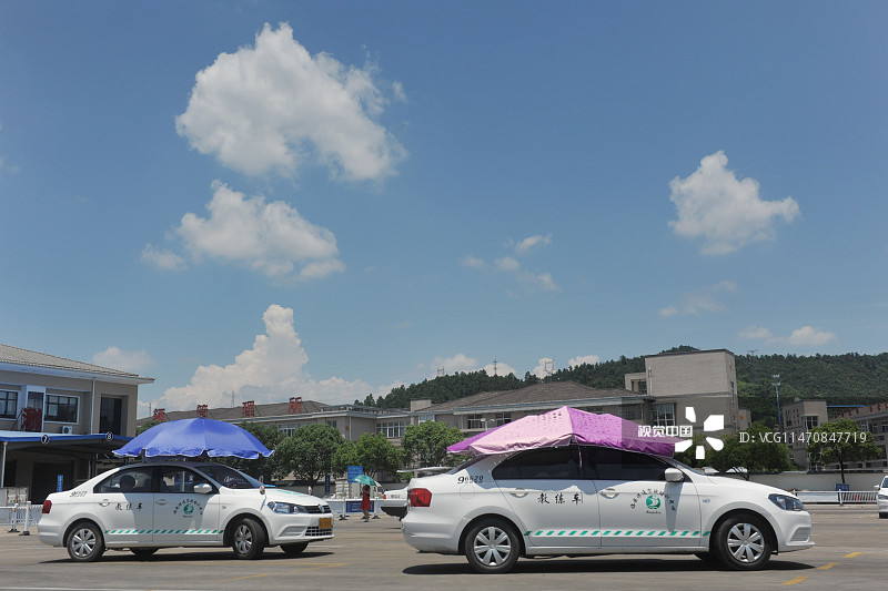 2015年7月27日，浙江杭州，临安市一所汽车驾驶学校采用车顶搭遮阳蓬、撑遮阳伞等方式为高温下的学员带来清凉。