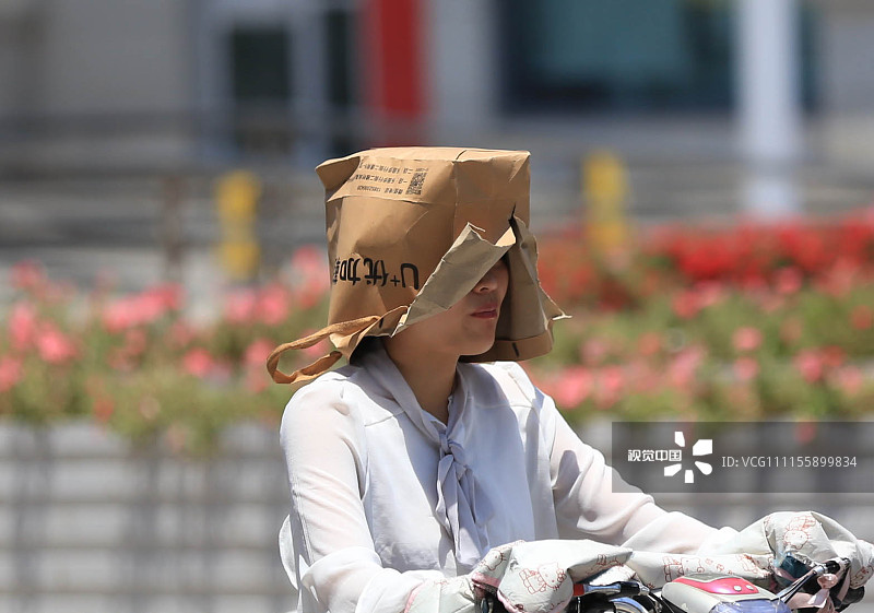 2018年6月13日，江苏淮安骄阳似火，市民出行各显神通避免阳光直接照射。