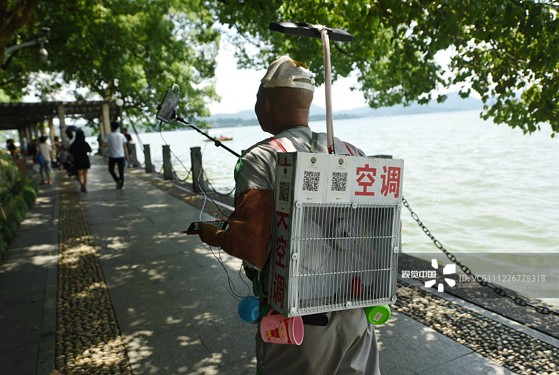 2019年7月25日，杭州，游客背着“空调”在直播酷暑中的西湖。