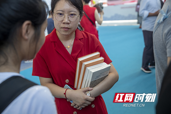 一名女士抱着心仪的书籍前往收银台。