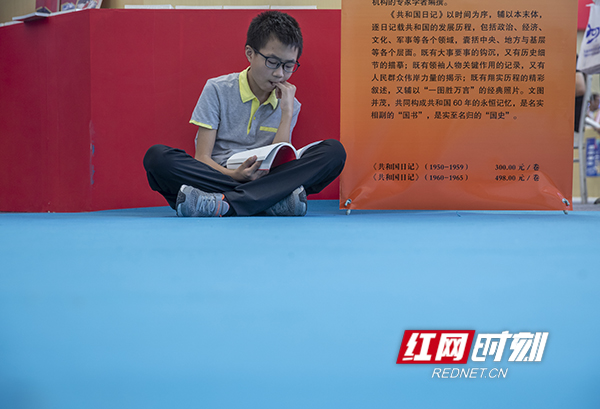 展台下，小读者席地而坐在读书。