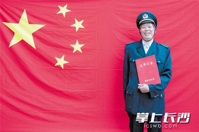 2019年1月18日是张合明的70岁生日，他手捧自己的荣誉证书，站在国旗下拍下了这张照片。 长沙晚报全媒体记者 余劭劼 通讯员 肖毅 摄影报道