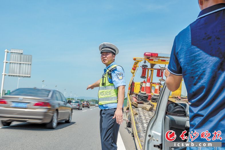 　　刘飞在高速公路上处理一起小车抛锚事故。施救车赶到现场后，他继续指挥过往车辆注意避让。