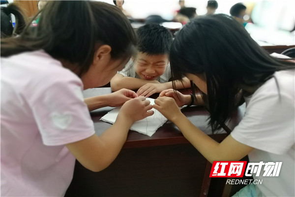 小朋友们屏息凝神，用五色彩线穿过依次排列在软垫上的7根针的针孔.jpg