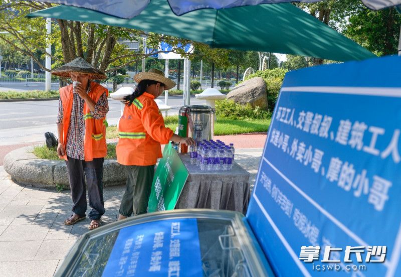 8月16日下午，岳麓区金星中路上，两位位环卫工人正在喝免费领取的凉茶。