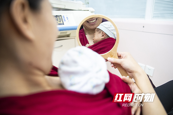 14.8月12日，湘雅医院，一位新生儿的母亲拿着镜子看着在自己胸前的小孩露出了幸福的笑容。摄影 陈杰 .jpg