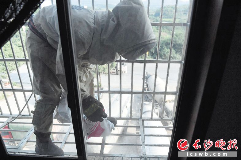 全副武装的消防员踩着防护窗，摘下马蜂窝装进编织袋。长沙晚报全媒体记者 余劭劼 摄