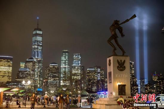 资料图：当地时间2018年9月11日，美国“911事件”17周年，纽约世贸中心附近两根象征着世贸中心双子塔的蓝色光柱直冲云霄，一直持续到黎明。图为从泽西市透过城市雕塑遥望灯柱。中新社记者 廖攀 摄