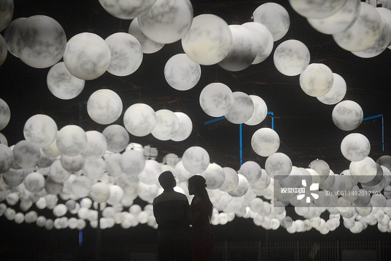 2016年09月14日，江苏省扬州市，一对情侣正在扬州广陵新城市民中心广场欣赏2499盏“月亮灯”。