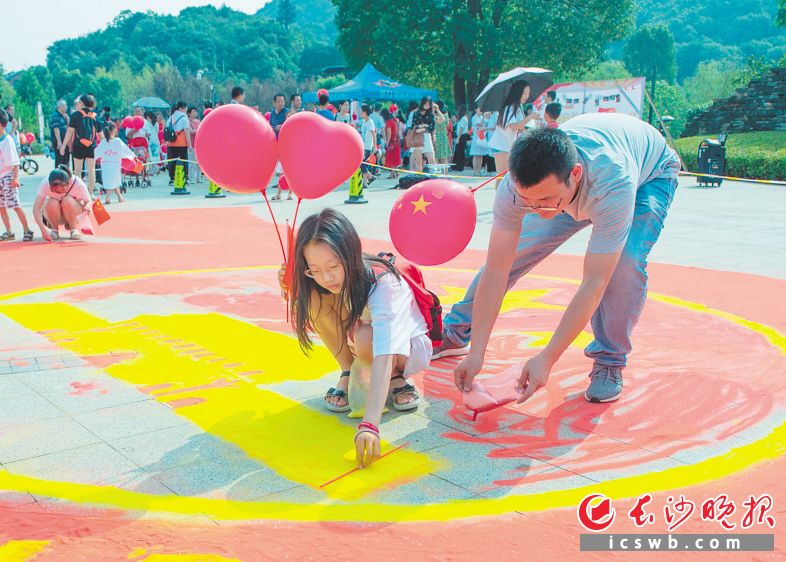 　　←党员志愿者、街道居民等500余人参加了活动。图为一名小朋友在地上认真地用沙作画。