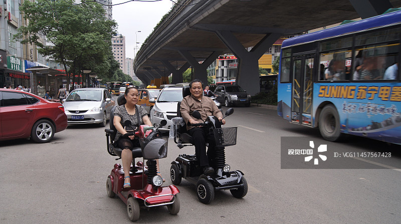 2011年6月16日，贵阳都市路街头一男一女驾驶两辆老年环保电动代步车，吸引行人好奇围观。