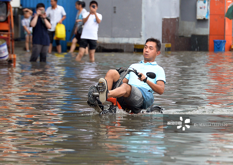 2015年07月23日，湖北武汉，汉口解放大道单洞门路段因暴雨严重渍水，一名男子在渍水中骑水上自行车出行。