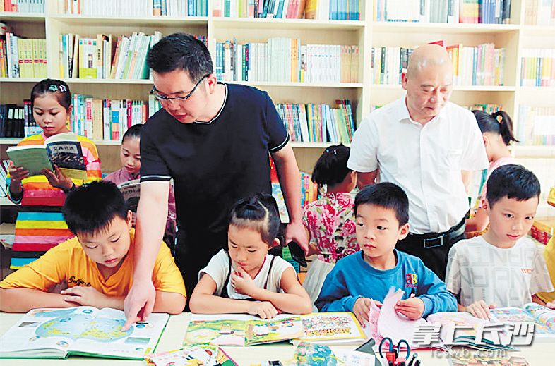 　　胡健老师（戴眼镜者）在公益书屋给孩子们解疑释惑。受访者供图