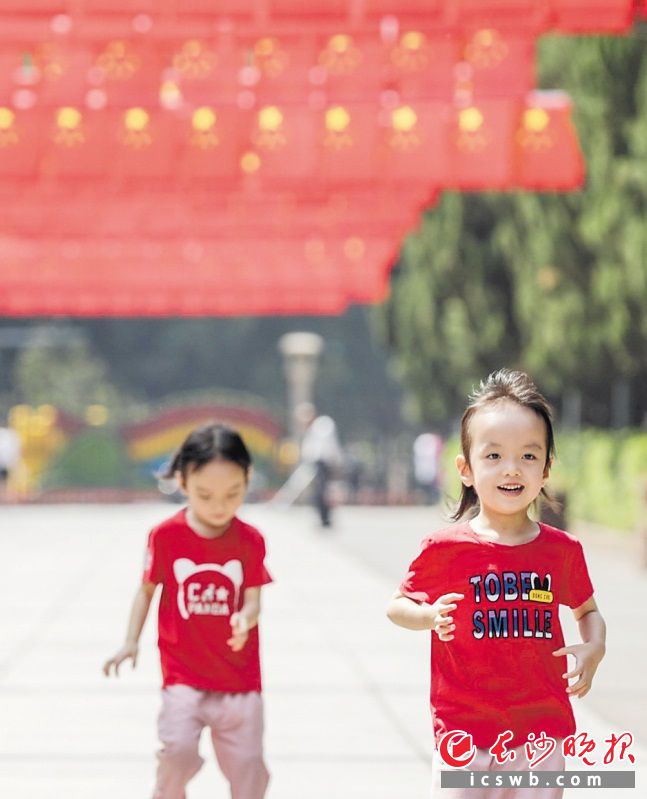 　　烈士公园南门　　两个孩子在国旗下开心奔跑。