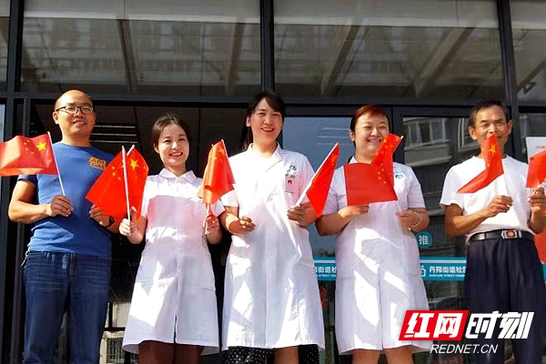 红网时刻常德10月1日讯（通讯员 曾惠）10月1日上午，常德市武陵区各基层医疗单位值班医护人员在坚守岗位的同时不忘收看庆祝中华人民共和国成立70周年大会、阅兵式和群众游行实况直播，用格尽职守的方式表达对祖国的爱。上图为丹阳街道社区卫生服务中心医护人员手持国旗，为祖国喝彩。