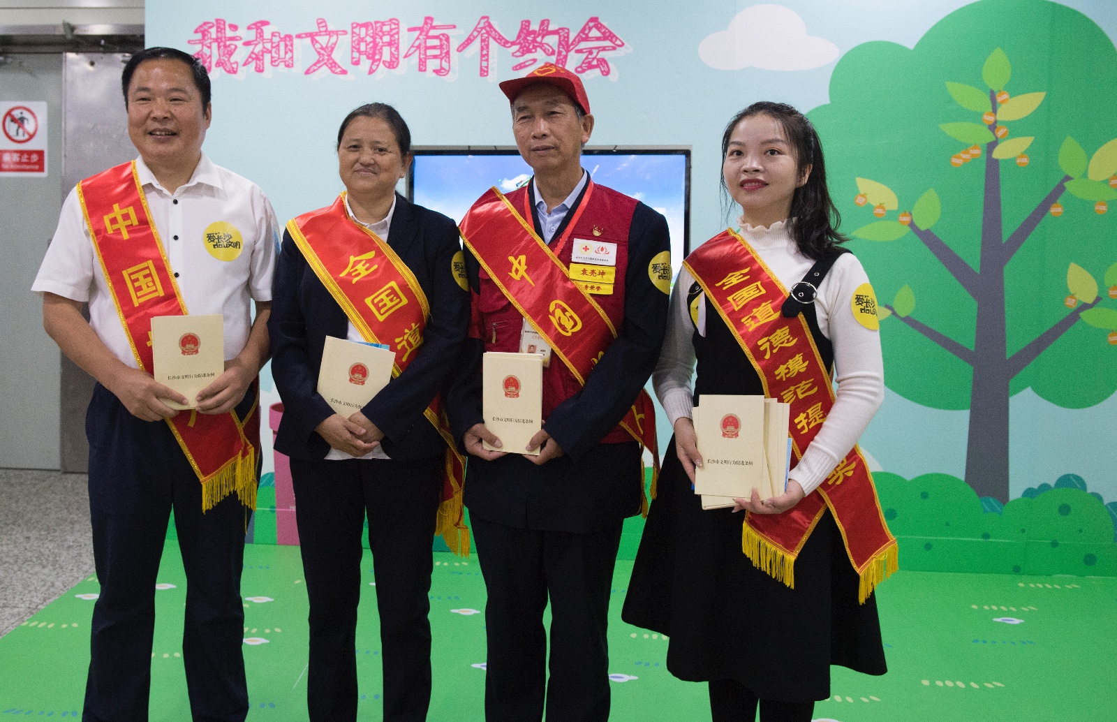 车厢故事主角——袁亮坤、何平、杨士泉、廖月娥四位文明模范向周边乘客派发《长沙文明促进条例》。长沙晚报全媒体记者  邹麟 摄