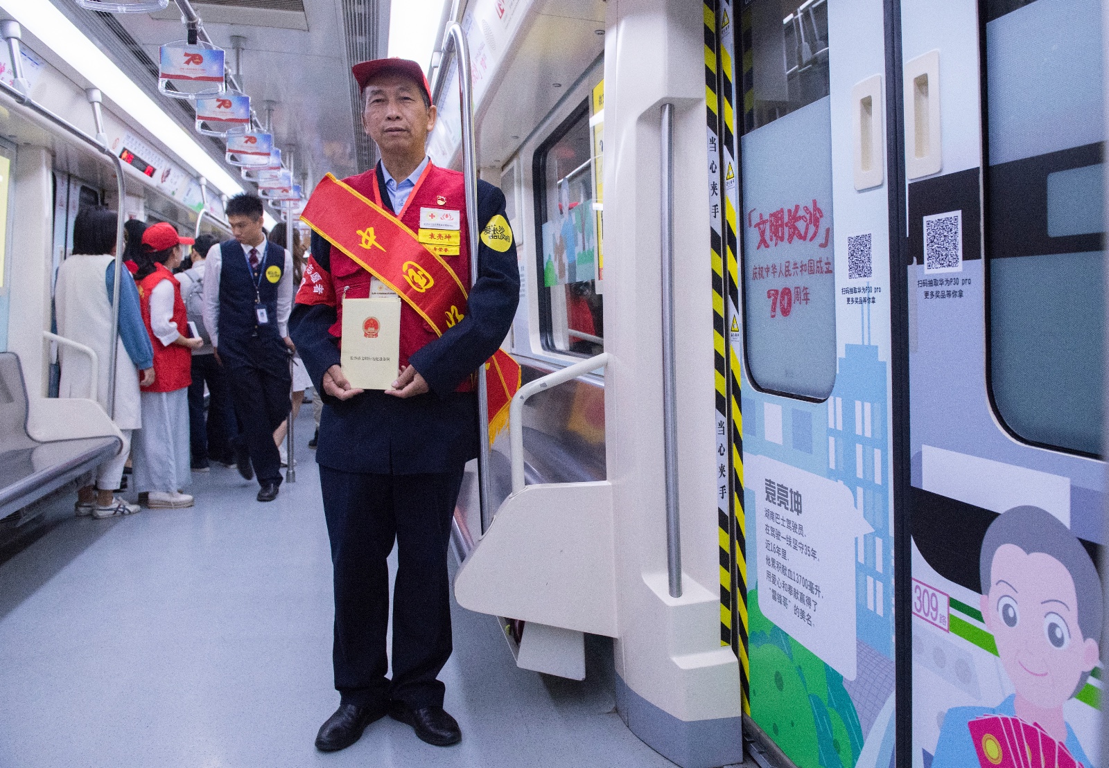 “热血公交哥”袁亮坤在列车上和自己的展示栏合影。长沙晚报全媒体记者 邹麟 摄
