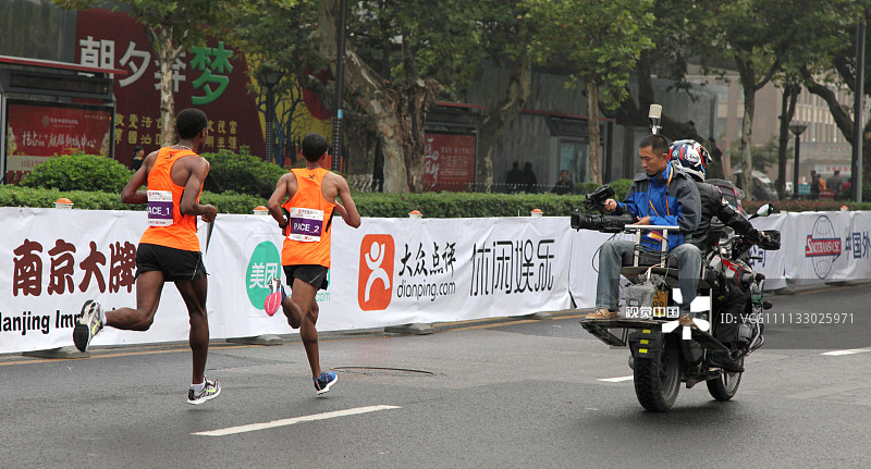 2016年10月16日，江苏省南京市，2016南京马拉松比赛的电视直播记者就坐着摩托车拍摄领跑的兔子选手。