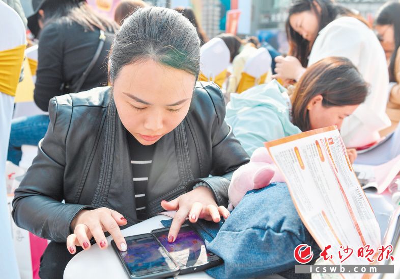 　　活动现场，一名女士用两部手机抢红包。均为邹麟 摄