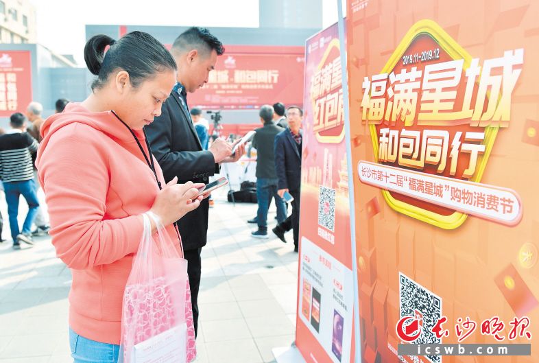 　　市民正在通过手机扫描二维码参与购物消费节活动。