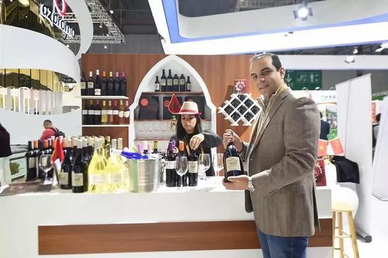 11月7日,在第二届进博会摩洛哥红酒展位,摩洛哥红农场酒庄总经理萨耶展示红酒。新华社记者尹炣摄