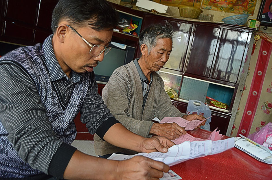 黎茂生父子翻看爱心人士捐款的明细单。黎家人将所有捐款的资料收集在一个袋子里，他们不能忘记好心人的爱心。