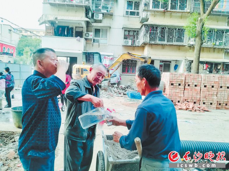 　　热心居民骆建峰（中）给工人端茶送水，支持拆违整治。长沙晚报通讯员 曹露 摄