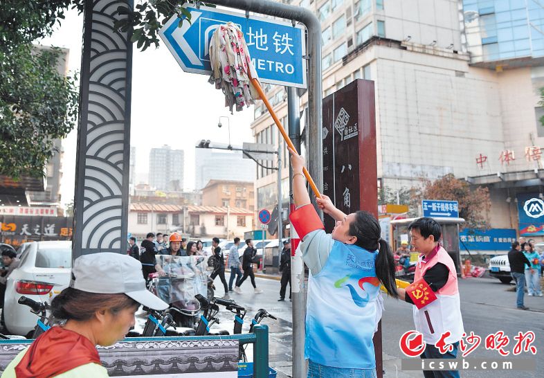 五一大道太平街口，志愿者们正在清洗路牌。长沙晚报全媒体记者 邹麟 摄