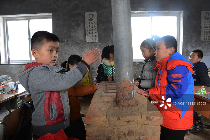 2017年12月30日，辽宁丹东。
孩子们课间在外面玩耍一阵后回到教室取暖，炉子一直烧到学生放学才熄灭，第二天早晨再重新点燃。