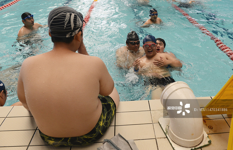 2015年7月13日，河南省郑州市，“小胖墩”在泳池中与同伴嬉戏。